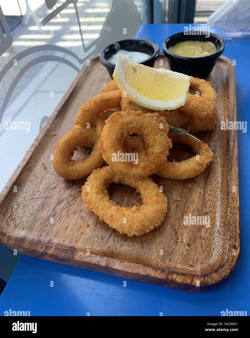 Gros plan des calamars frits sur une table bleue dans un restaurant - Image de stock capturée avec un smartphone