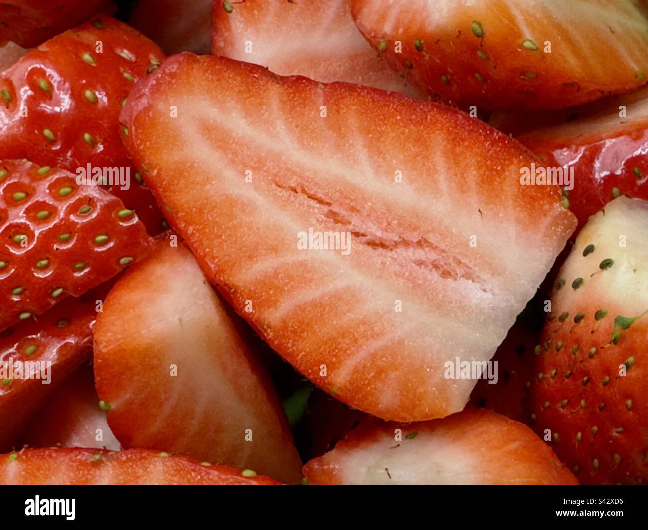 Un gros plan de quelques grosses fraises fines, l'une d'entre elles en coupe transversale. Banque D'Images