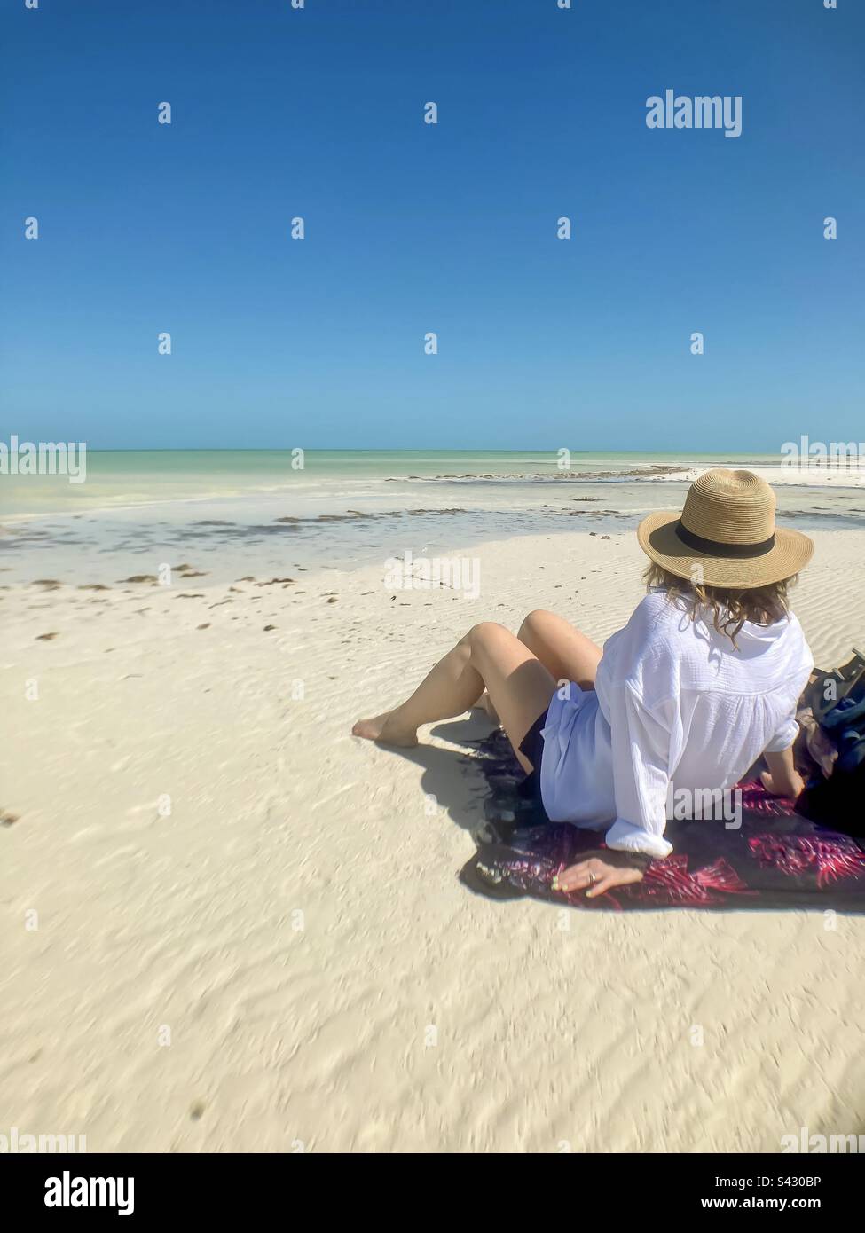 Belle femme assise sur un sarong prenant dans la beauté de Punta Mosquito sur Holbox Island. Banque D'Images
