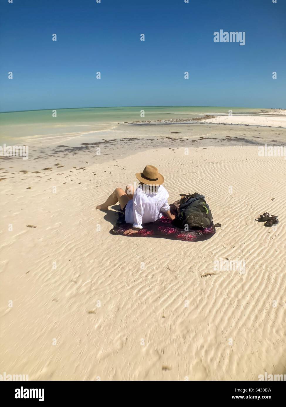 Belle femme assise sur un sarong prenant dans la beauté de Punta Mosquito sur Holbox Island. Banque D'Images