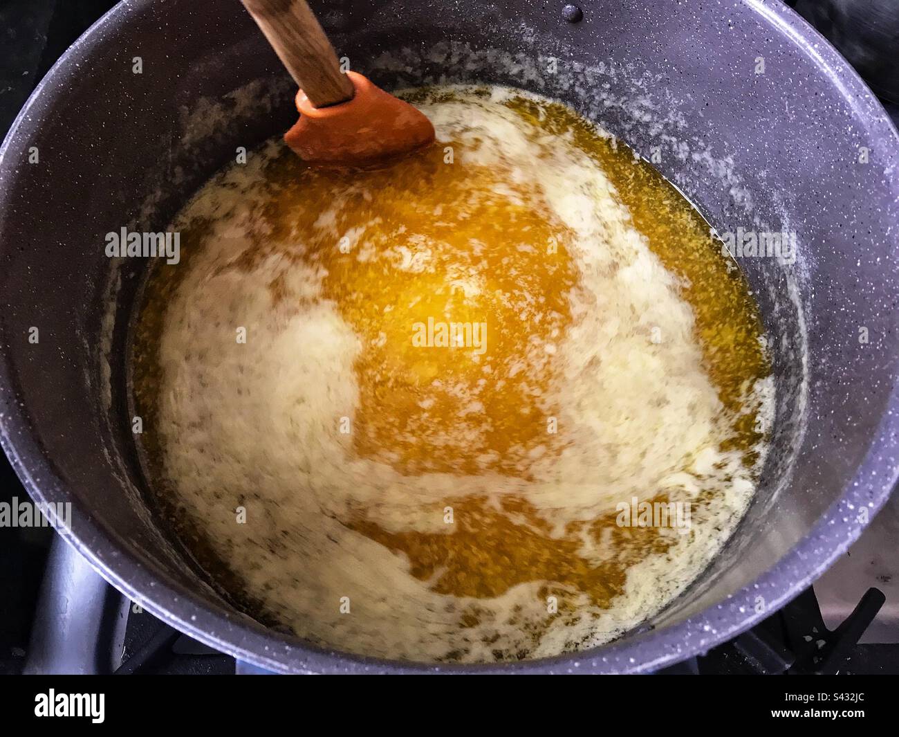 Remuant le ghee doré savoureux dans un pot après que c'était du beurre. Banque D'Images