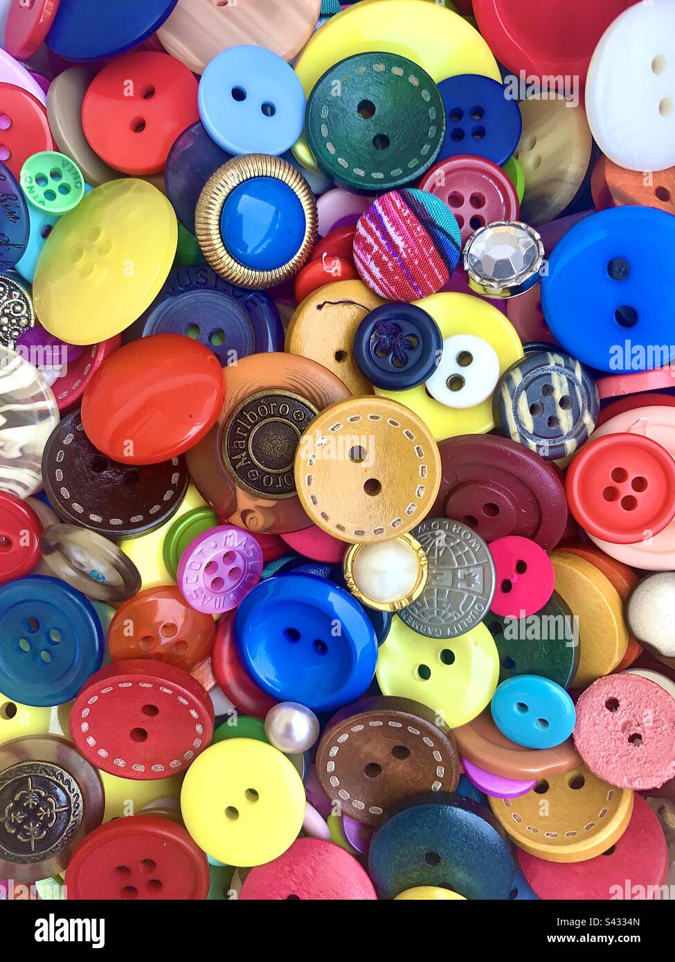 Superbe fond de bouton. Une sélection colorée et richement texturée de boutons multicolores remplit tout le cadre. Banque D'Images