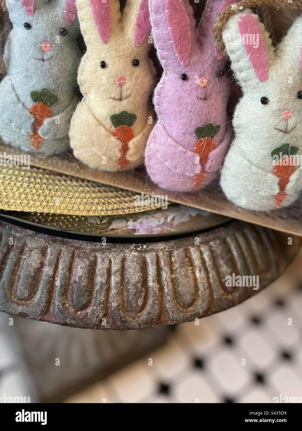 Quatre petits lapins de Pâques farcis aux couleurs pastel, debout dans une ligne de carottes. Inclut l'espace d'impression. Banque D'Images