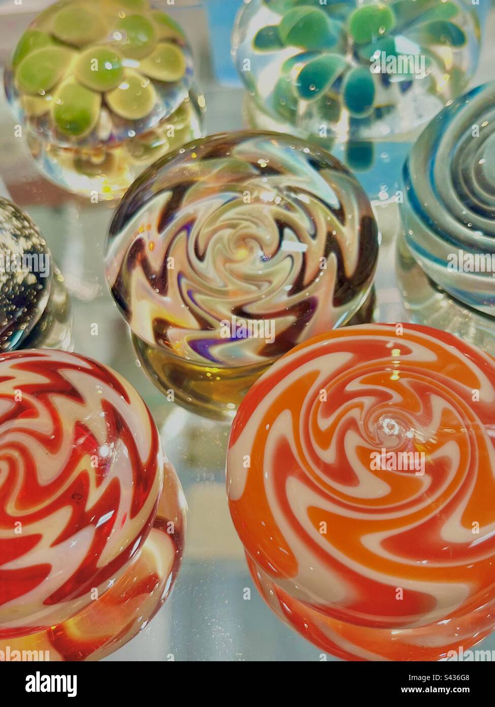 Magnifique exposition de boules de verre de couleur tournoyée sur fond blanc brut. - Image de stock capturée avec un smartphone