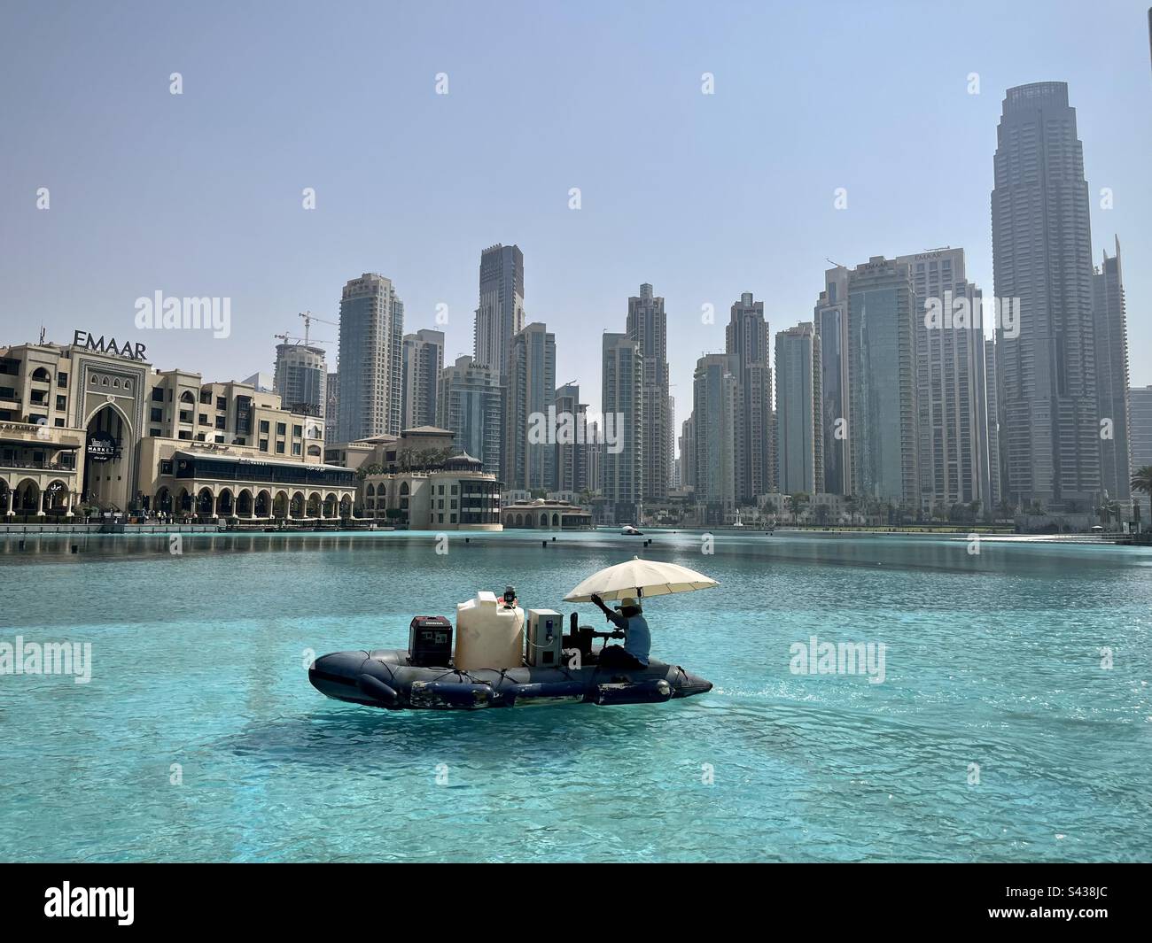 Petit bateau sur un bassin d'eau turquoise avec des bâtiments modernes de Dubaï en arrière-plan. Photo prise à Dubaï en août 2022 Banque D'Images