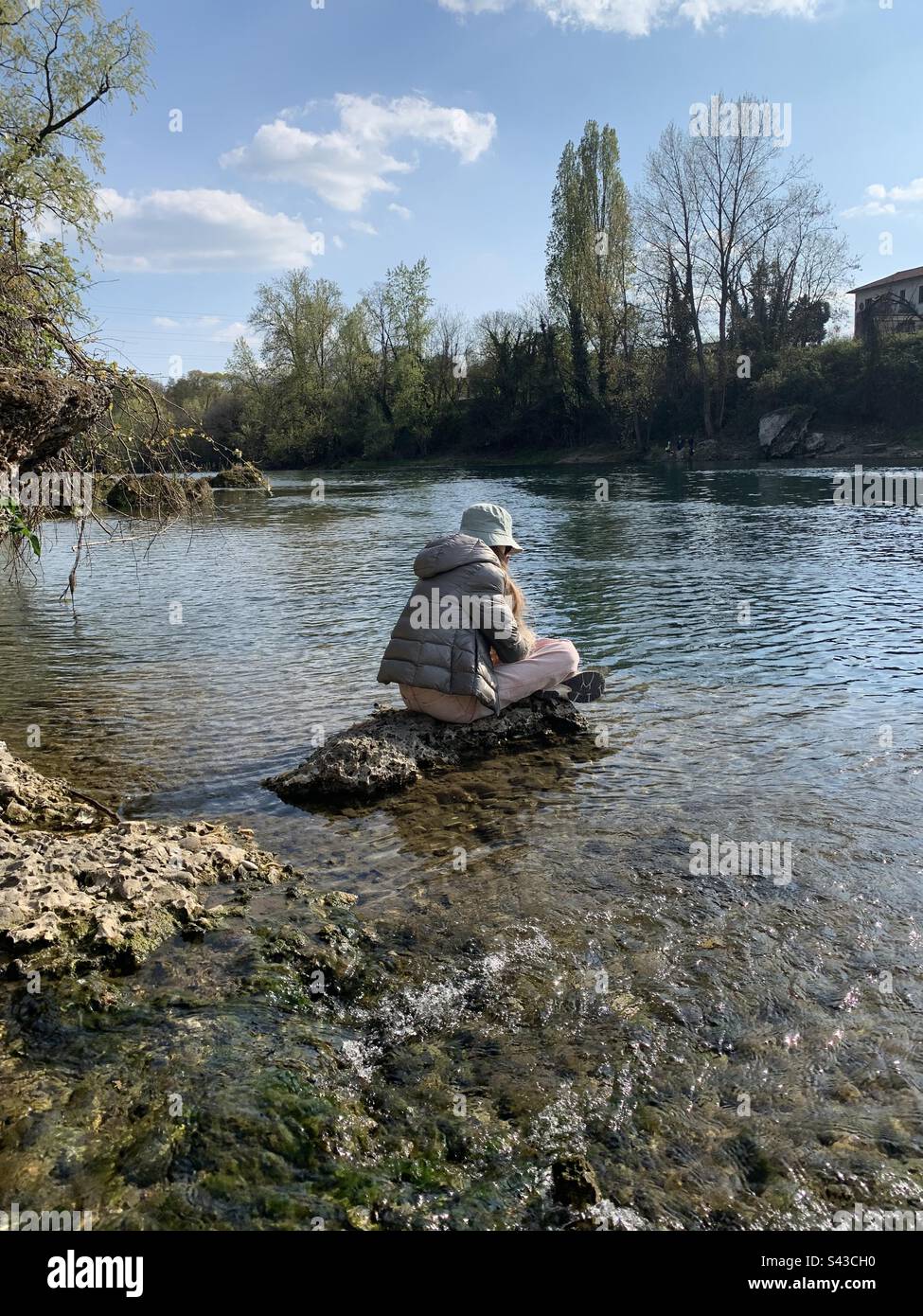 Fille assise sur une falaise sur la rivière Adda, Italie Banque D'Images