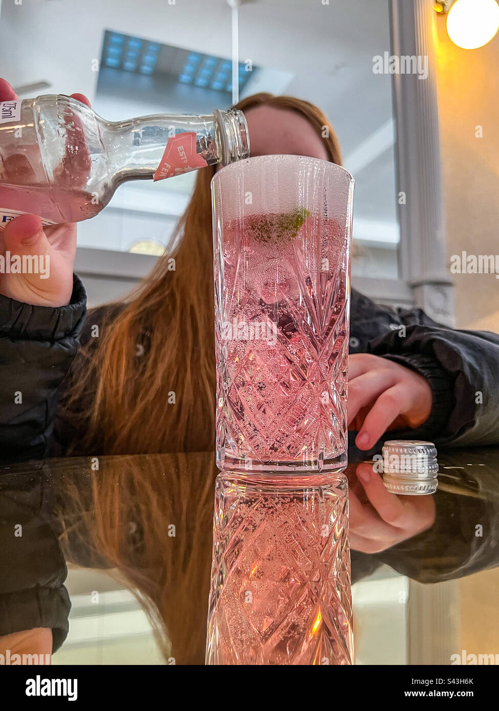 Adolescent versant de la limonade rose dans un verre dans un bar Banque D'Images