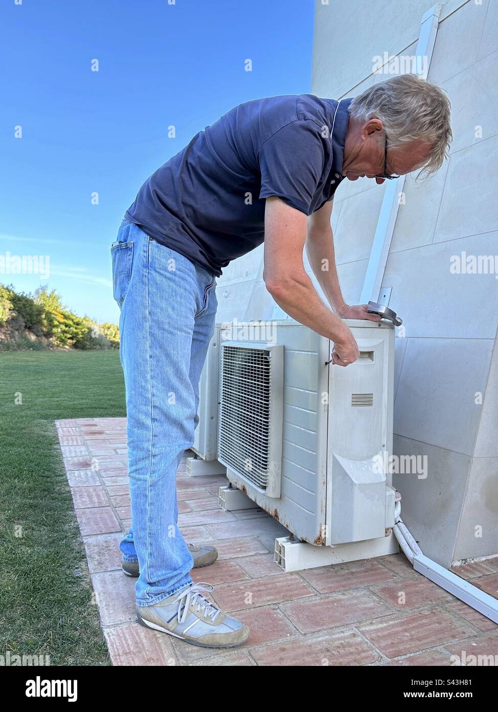 Homme inspectant une unité de climatisation externe - Image de stock capturée avec un smartphone