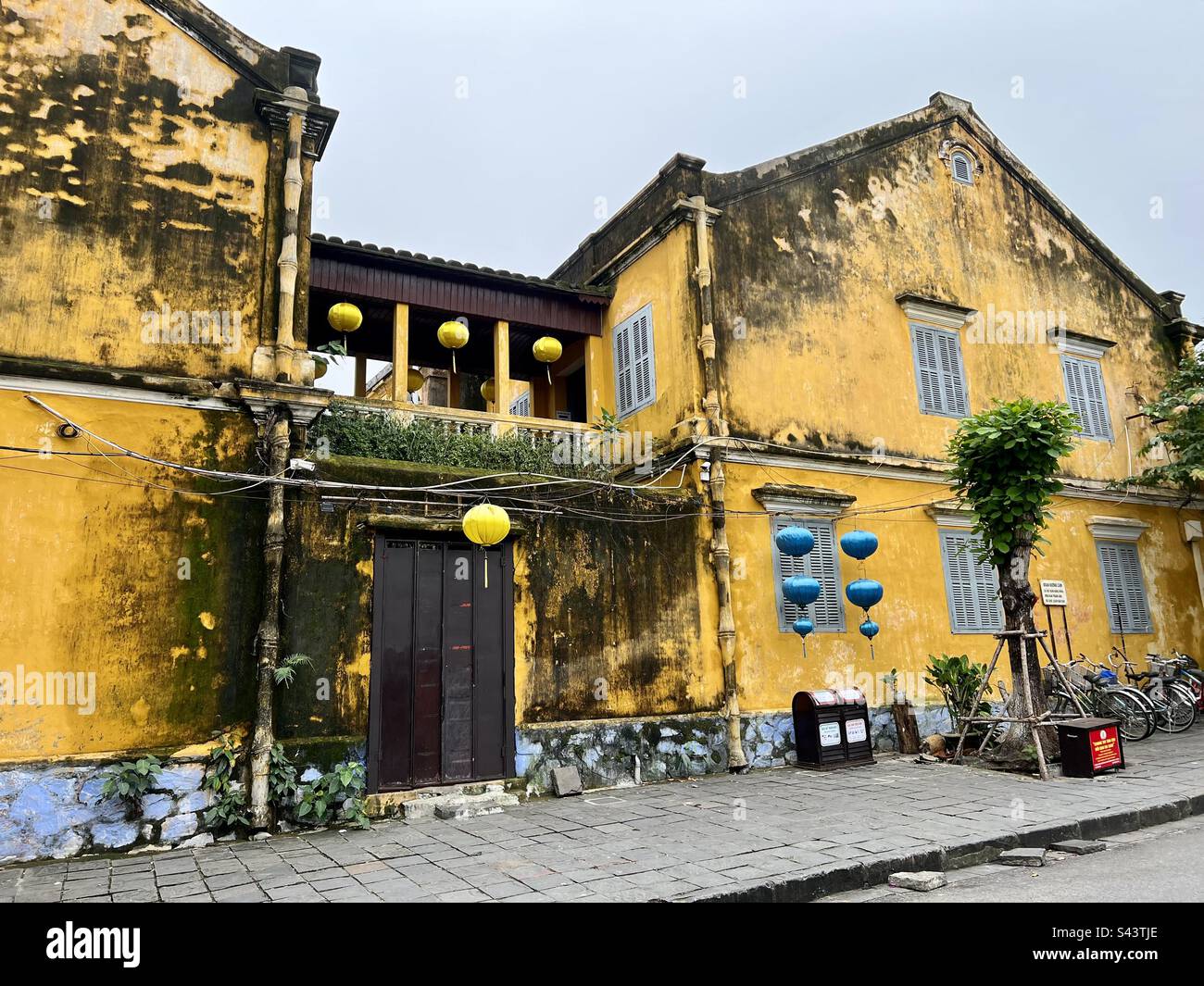 Bâtiment jaune vif avec lanternes colorées dans une rue asiatique Banque D'Images