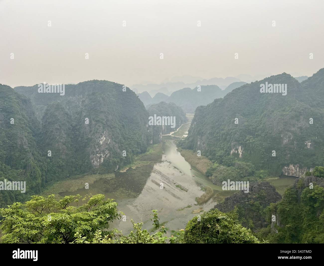 Vue aérienne sur les montagnes brumeuses surplombant la rivière avec des rizières Banque D'Images