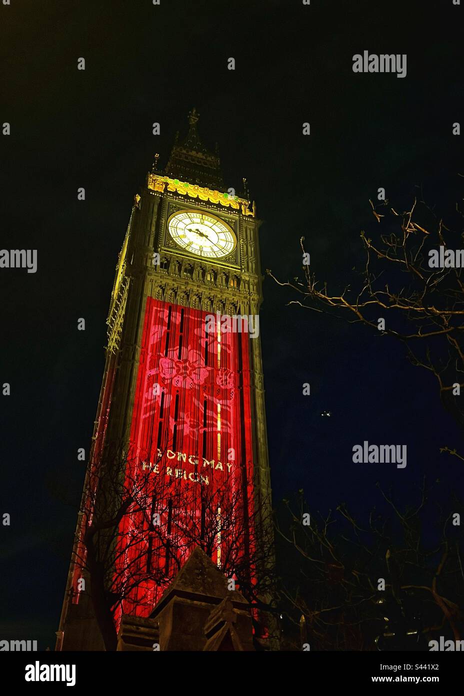 Big Ben, Elizabeth Tower, une partie du Palais de Westminster à Londres, décorée de « long May he Reign » pour célébrer le couronnement du roi Charles III à Londres. Veilleuses. Arborescence en arrière-plan - Image de stock capturée avec un smartphone