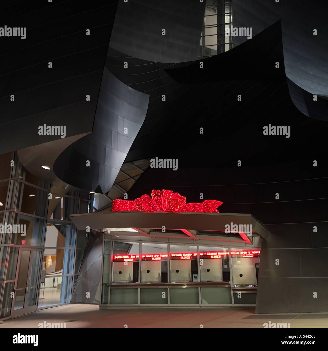 LOS ANGELES, CA, DEC 2022 : box office au Walt Disney concert Hall décoré d'un noeud rouge, éclairé la nuit pour les vacances d'hiver - Image de stock capturée avec un smartphone