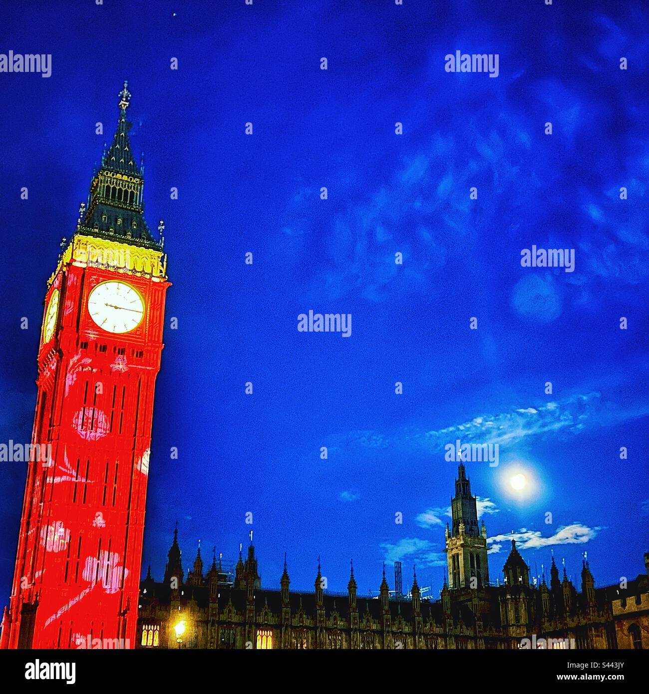 La lune s'élève au-dessus du Parlement avec la tour de l'horloge, Big Ben illuminé pour le couronnement du roi Charles III à Londres, les lumières brillent de mille feux la nuit - Image de stock capturée avec un smartphone