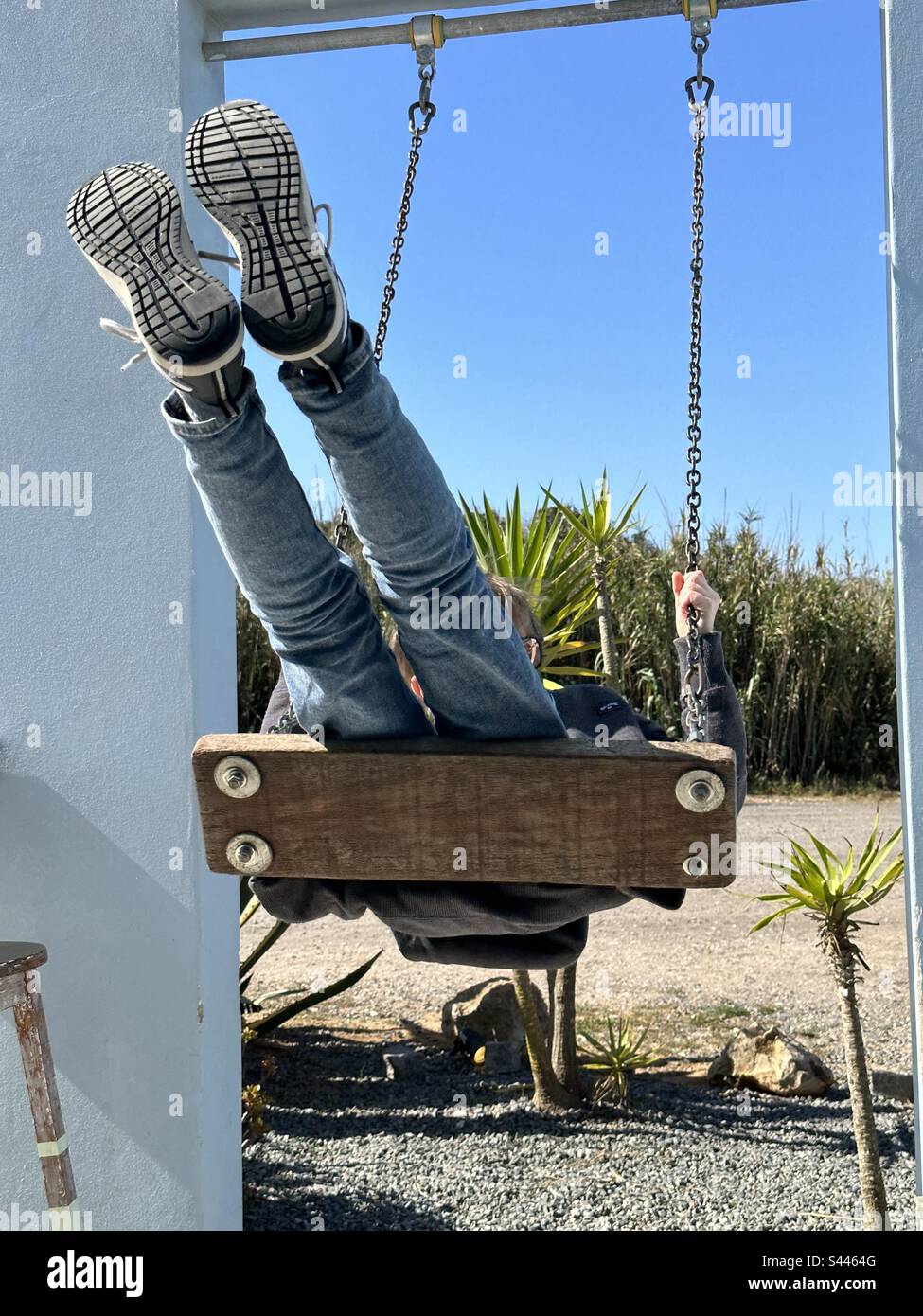 Vue avant de l'enfant balançant vers l'avant sur une balançoire en bois - Image de stock capturée avec un smartphone