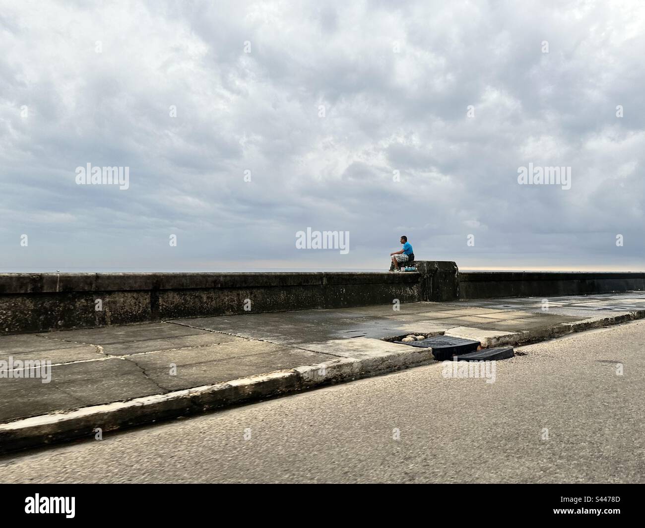 Homme assis à la havane digue ‚el malecón un jour nuageux. La Havane, Cuba Banque D'Images