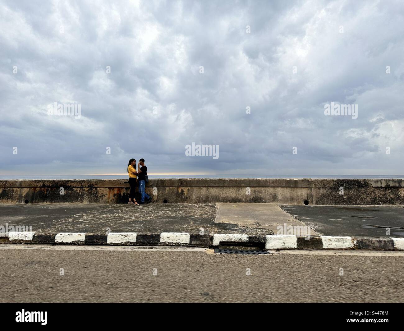 Couple debout près de la digue de la havane ‚el malecón» par une journée nuageux. Cuba Banque D'Images
