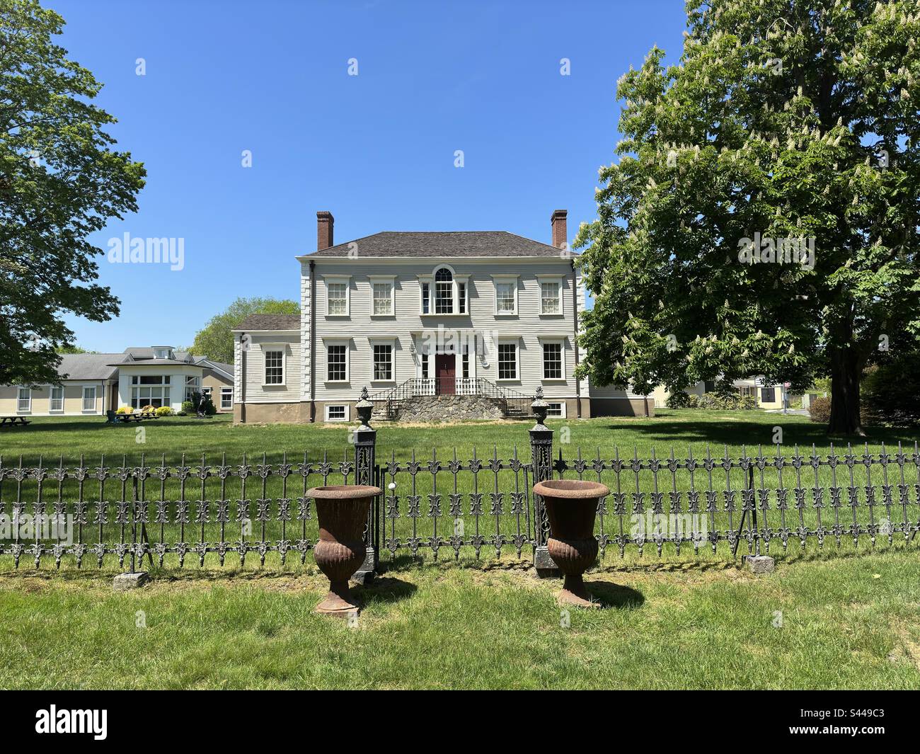 Old Lyme, Connecticut, Etats-Unis: Académie des beaux-arts de Lyme Extension de l'Université de New Haven. Vue sur l'ancien bâtiment de deux étages avec clôture en fer forgé et urnes devant. Campus de l'école d'art. - Image de stock capturée avec un smartphone