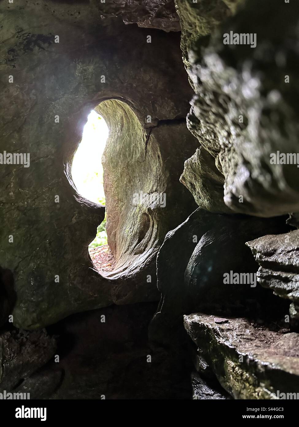 Un trou de roche épaisse sert de fenêtre dans la grotte de la druide au château et jardins de Blarney, à Blarney, en Irlande. Banque D'Images