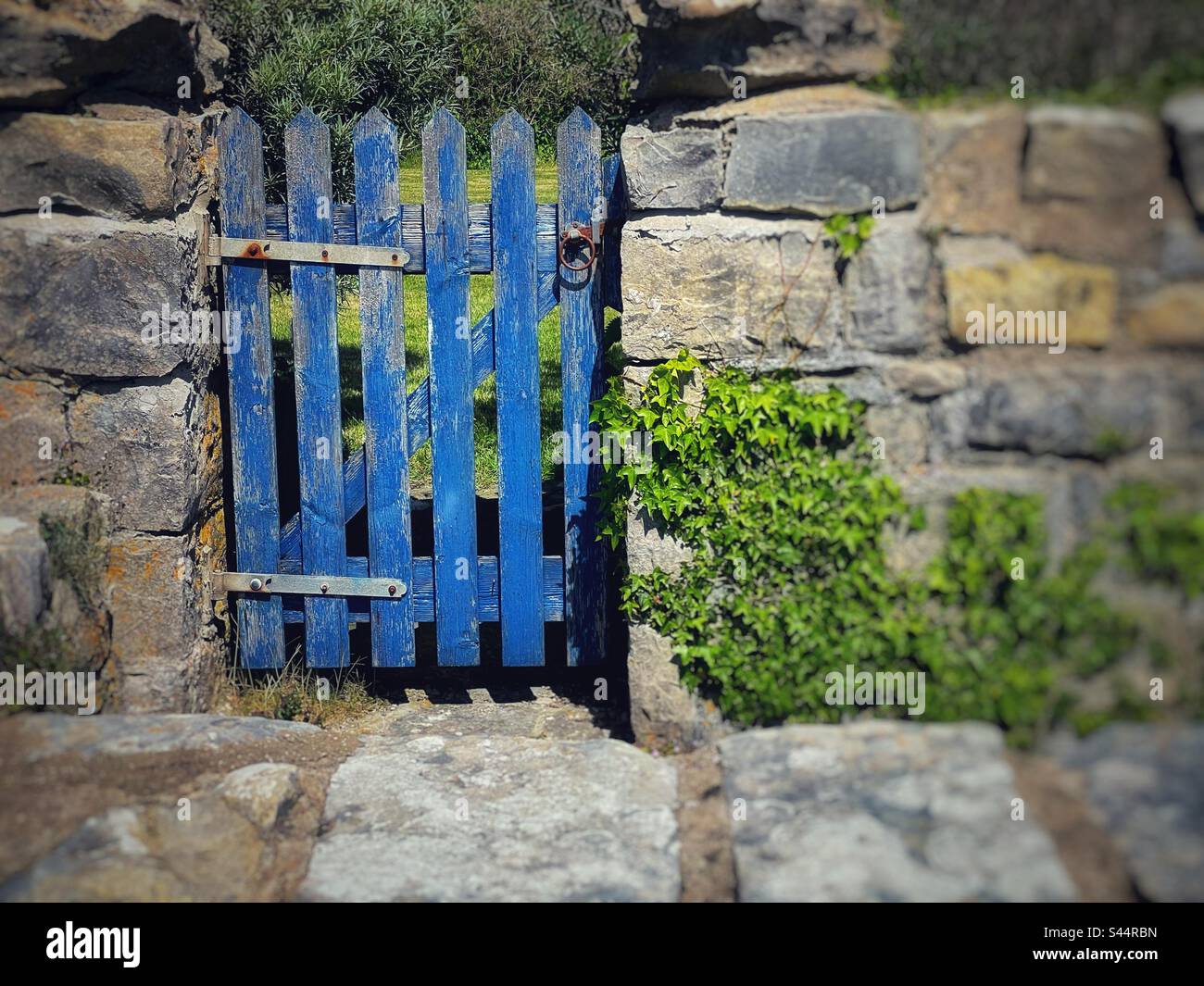Ancienne porte en bois avec peinture bleu pâle dans un mur en pierre naturelle. Banque D'Images
