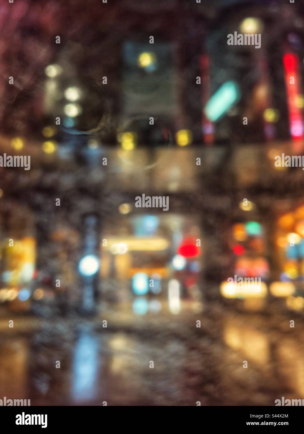 Photo abstraite de la rue de la ville et de l'extérieur éclairé du bâtiment vu par la fenêtre de voiture humide lors d'une nuit de pluie. Défoqué. Bokeh. Arrière-plans - Image de stock capturée avec un smartphone