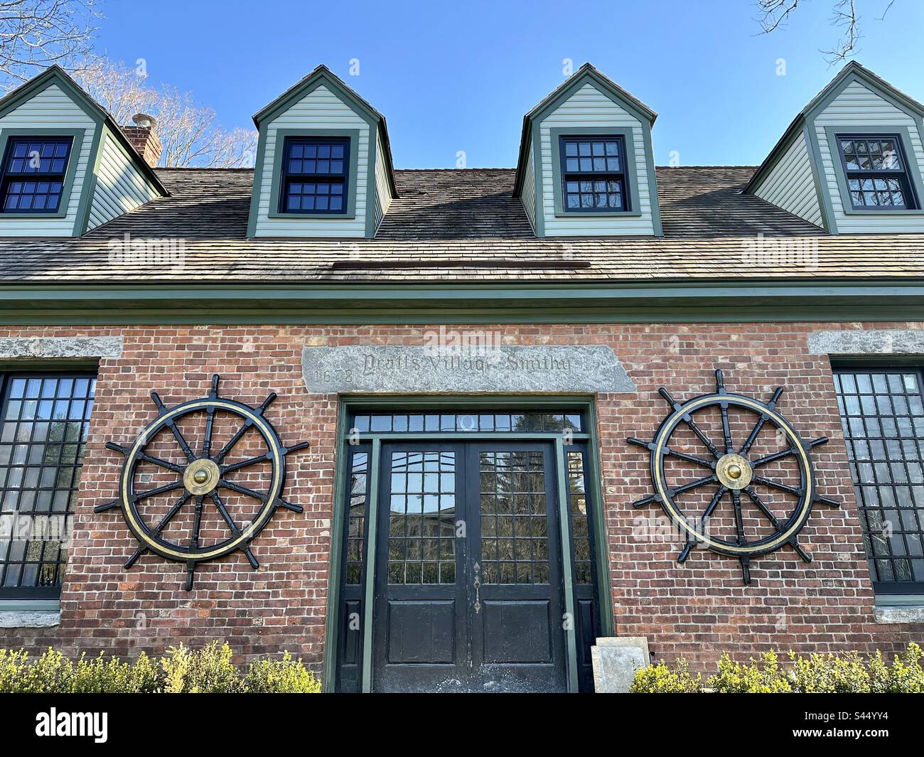 Le village Smith de Pratt. Bâtiment historique d'Essex, Connecticut, États-Unis. Architecture en brique rouge avec porte noire et roues capitaine de chaque côté. Banque D'Images