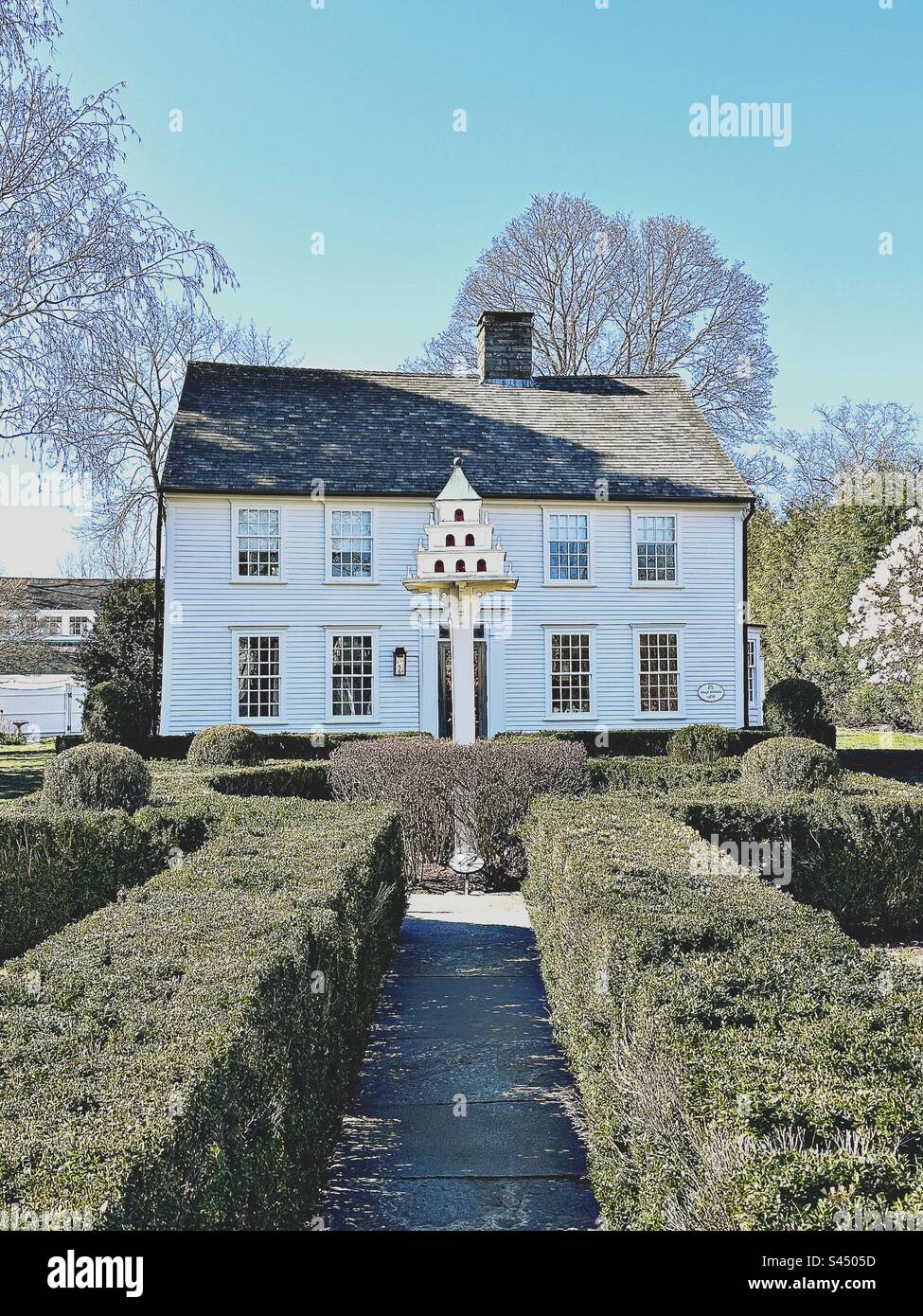 Belle, ancienne, coloniale maison de deux étages dans Essex, Connecticut, États-Unis. Buissons taillés qui mènent à une grande maison d'oiseaux élaborée en face de la résidence privée. Banque D'Images