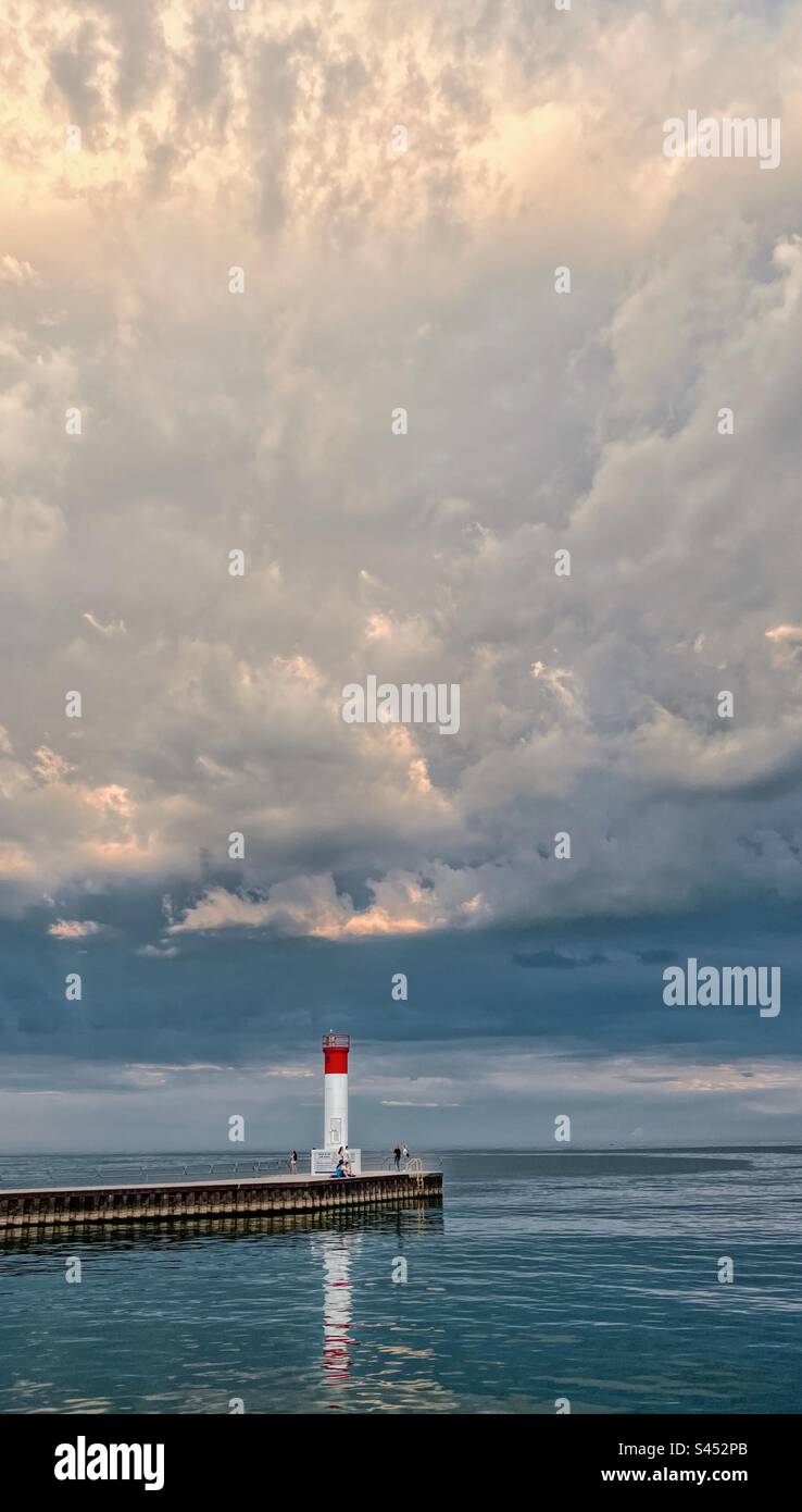 Phare au bout de la jetée avec de spectaculaires nuages de tempête au-dessus. Lac Ontario, Canada. - Image de stock capturée avec un smartphone