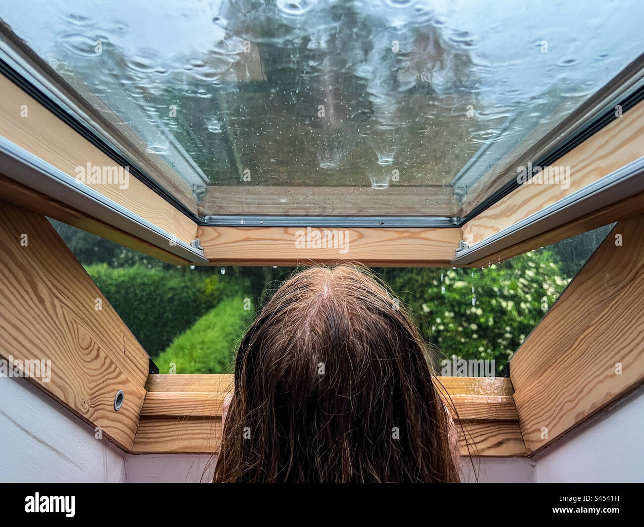 Adolescent regardant par la fenêtre pendant l'orage et la pluie Banque D'Images