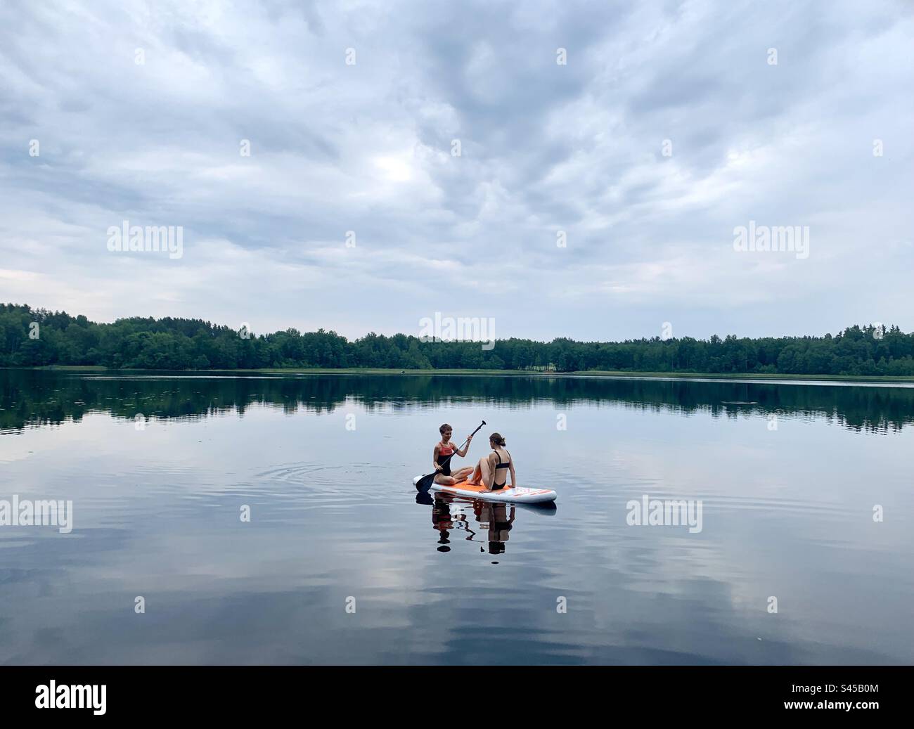 Deux filles se détendant sur sup paddle board sur le lac calme en été - Image de stock capturée avec un smartphone