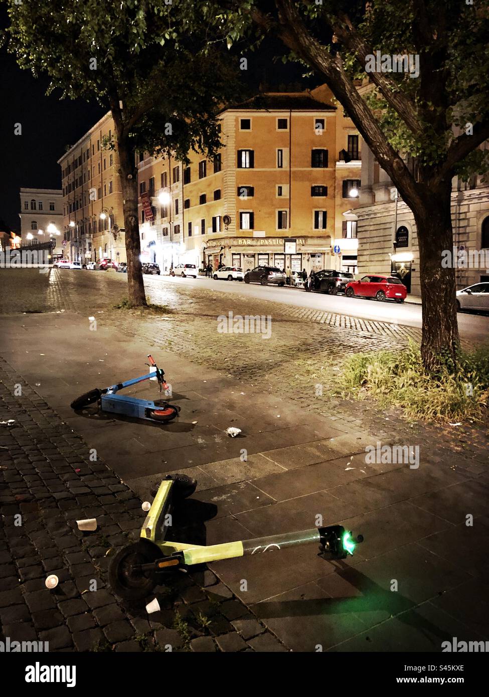 Scooters électriques abandonnés la nuit dans la rue à Rome, Italie Banque D'Images