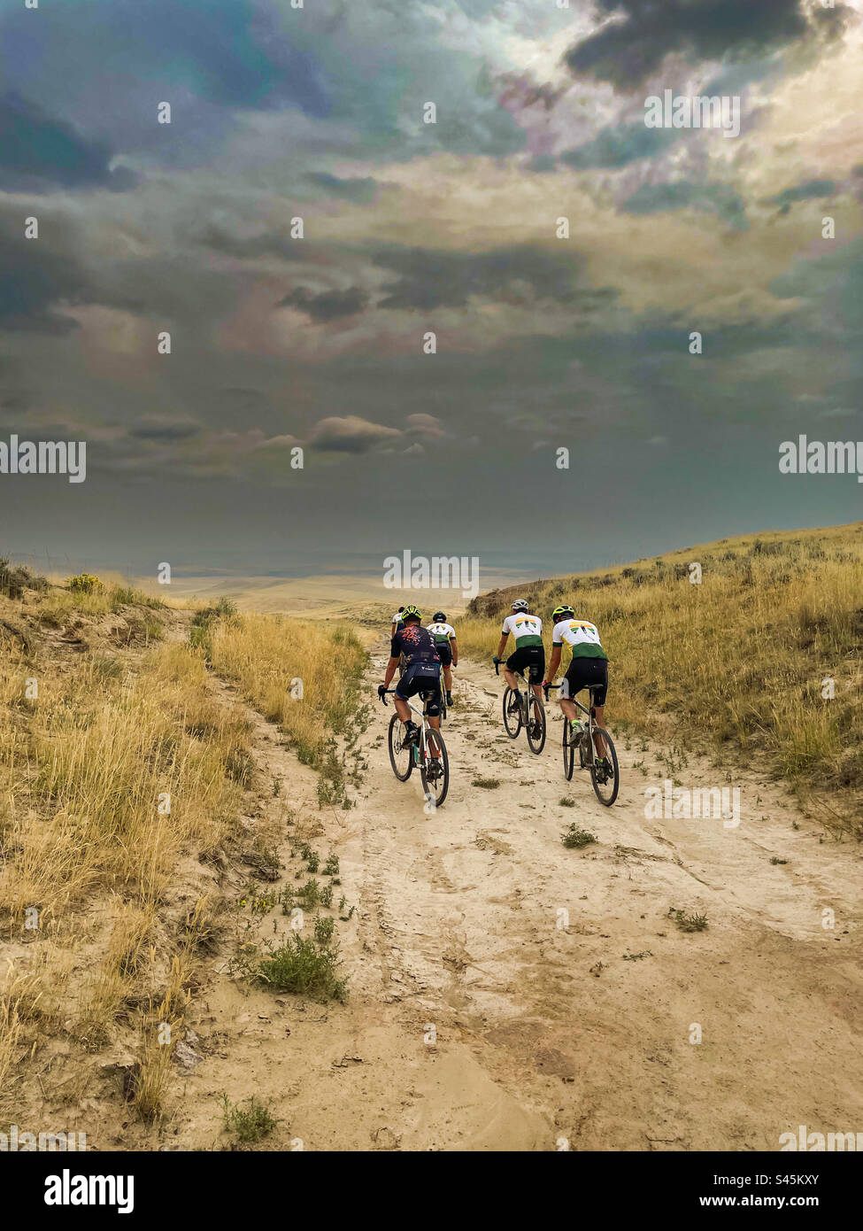 4 cyclistes parcourent le Wyoming. Vélos Gravel. Moody Sky. Cyclistes sur une piste de terre dans la nature sauvage Banque D'Images