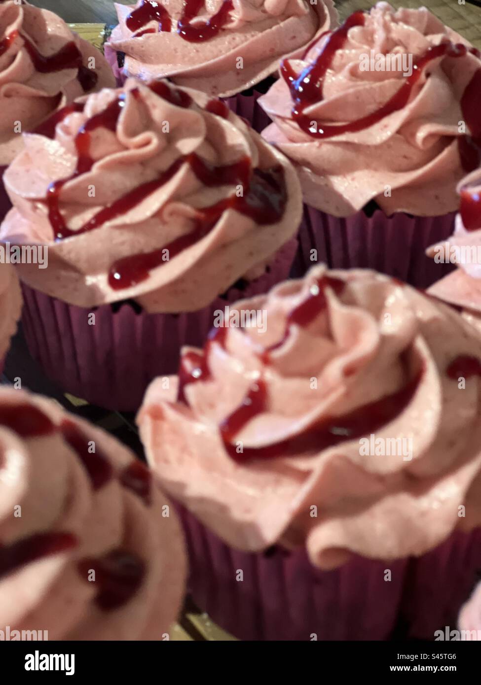 Cupcakes au chocolat avec crème au beurre de framboise et coulis de framboise Banque D'Images