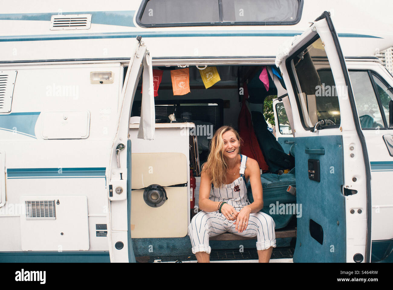 Jeune femme en salopette blanche assise dans un camping-car Banque D'Images