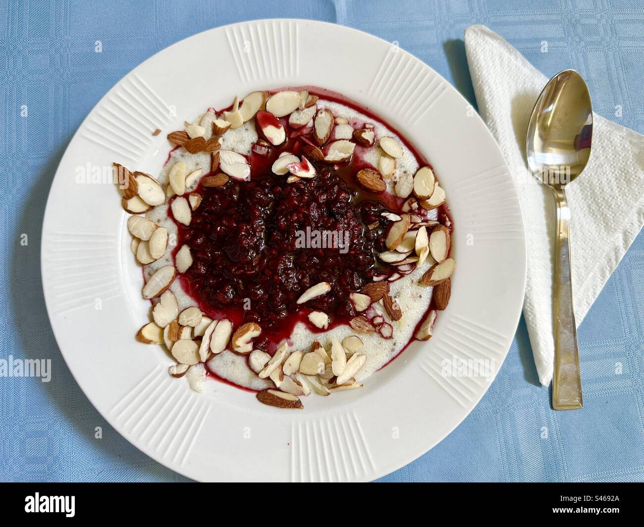 Petit déjeuner crémeux sain. Crème de blé et graines de chia cuites dans du lait faible en gras, garnies de baies noires cuites et bleues de deux cuillères à soupe de sirop d'érable et d'amandes crues tranchées. Banque D'Images