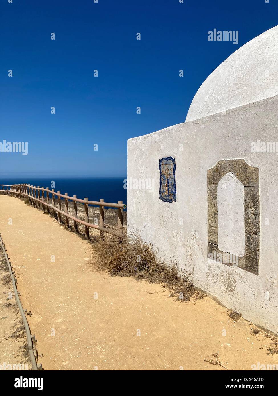 Chapelle Ermida da Memória (Ermitage de la mémoire) à Cabo Espichel avec vue sur le paysage bleu de la mer et le rail de protection. Côte de Sesimbra, sud du Portugal Banque D'Images