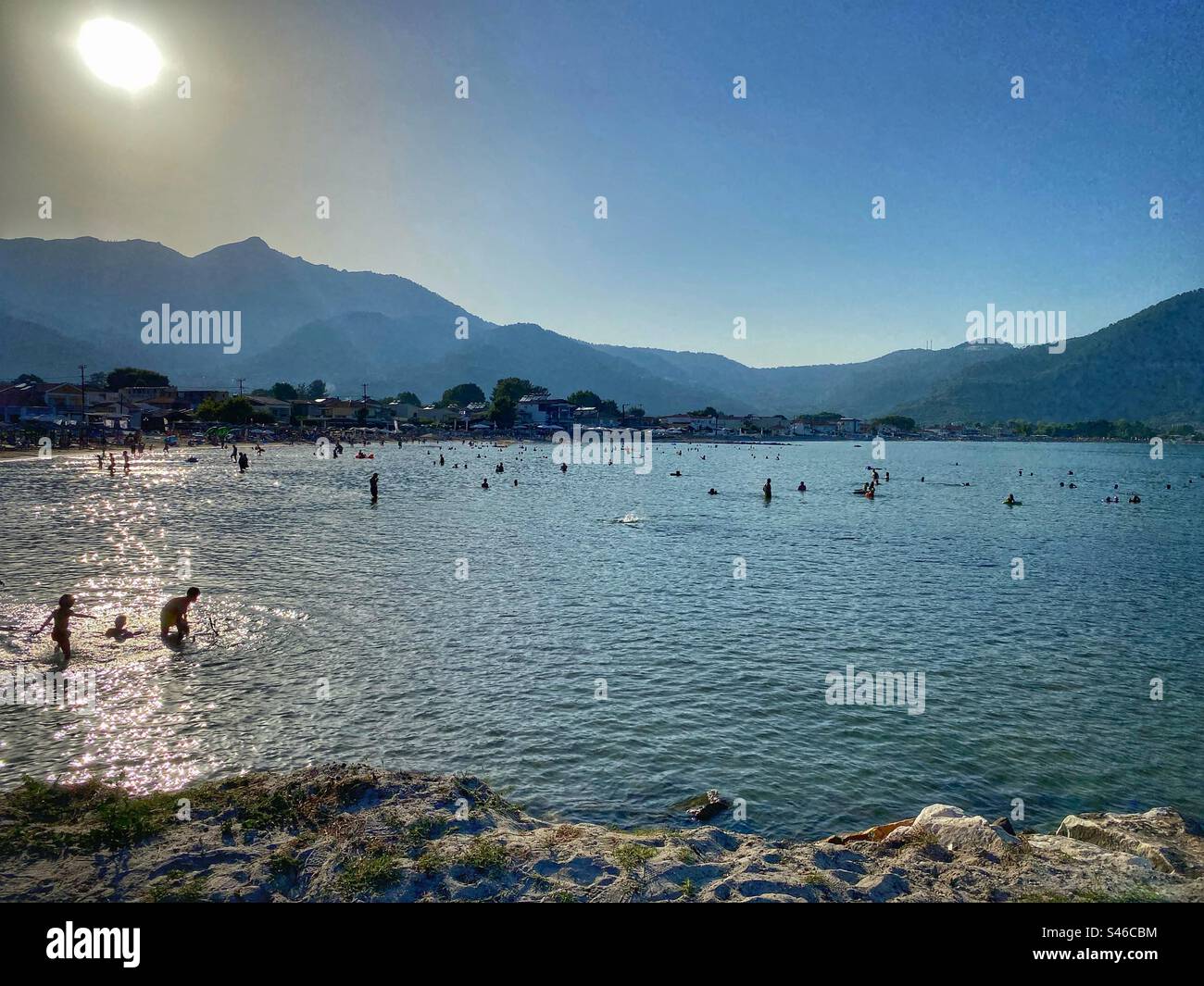 Les gens nageant au coucher du soleil avec vue sur les collines sur la plage de Skala Potamias Resort sur l'île de Thassos, Grèce. Banque D'Images