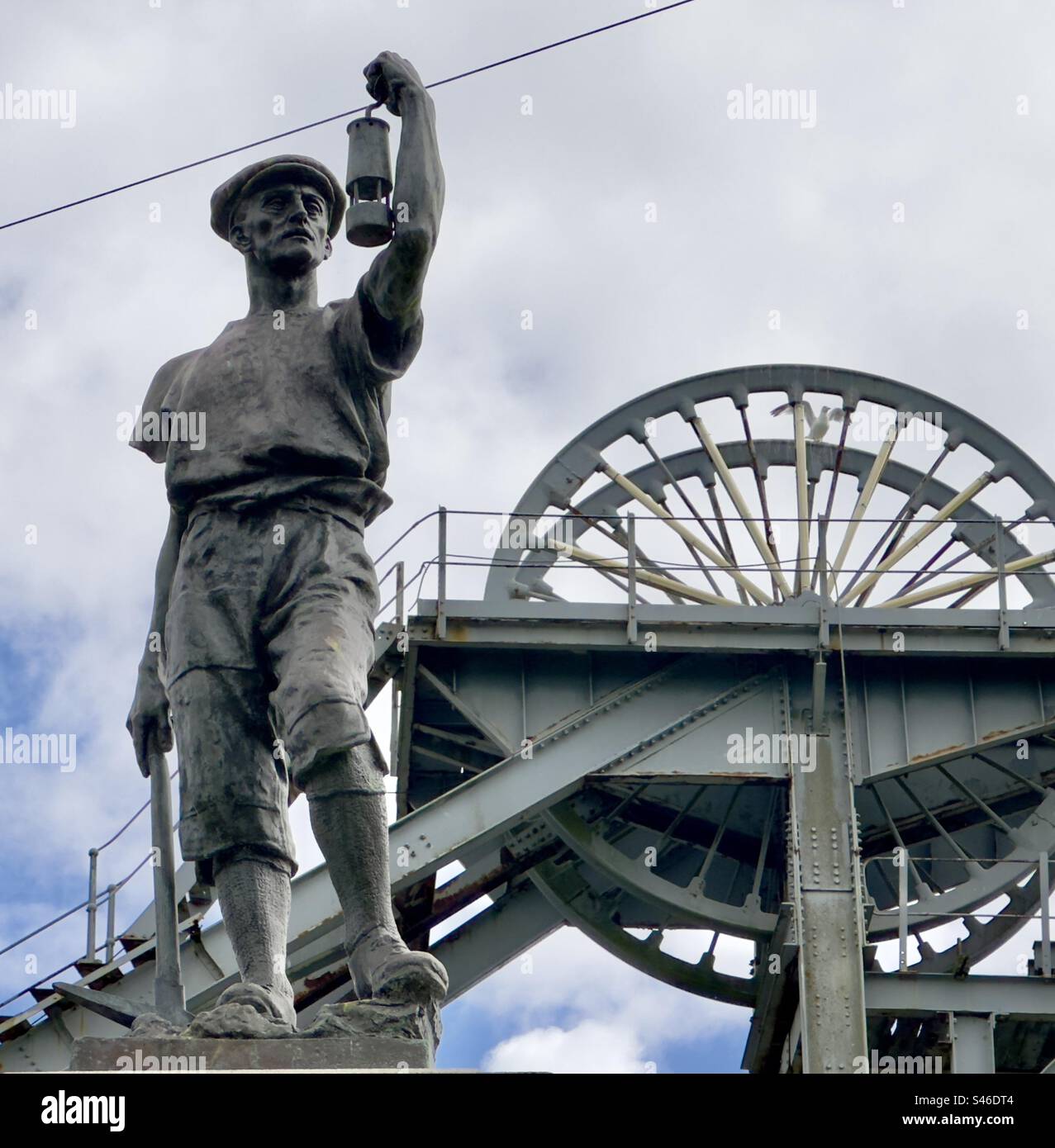 La figure d'un mineur tenant une lampe de sécurité sur un mémorial au Woodhorn Mining Museum devant le train de tête de fosse Banque D'Images