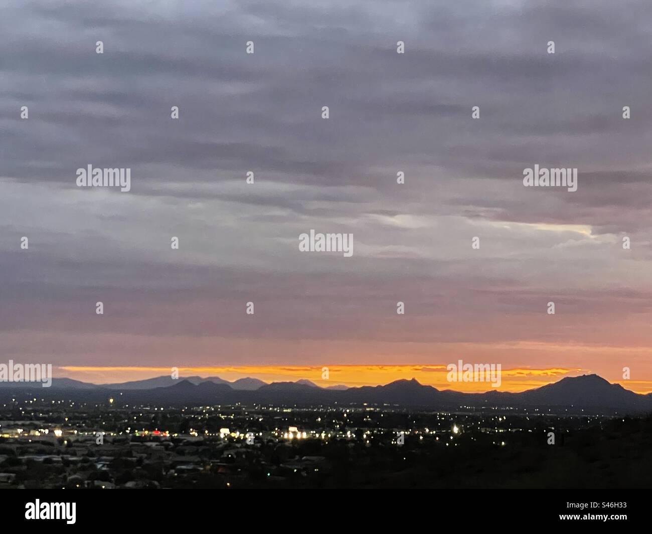 Une douce couverture violette de nuages annonçant le début d'un lever de soleil glorieux, McDowell Mountains, lumières de la ville de Scottsdale, jaune vif, orange, bandes de couleur, Lookout Mountain, Phoenix, Arizona Banque D'Images