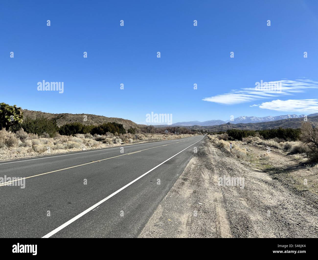 Vue depuis le bord de la route, à côté d'un tronçon plat d'autoroute à travers le désert dans le sud de la Californie Banque D'Images