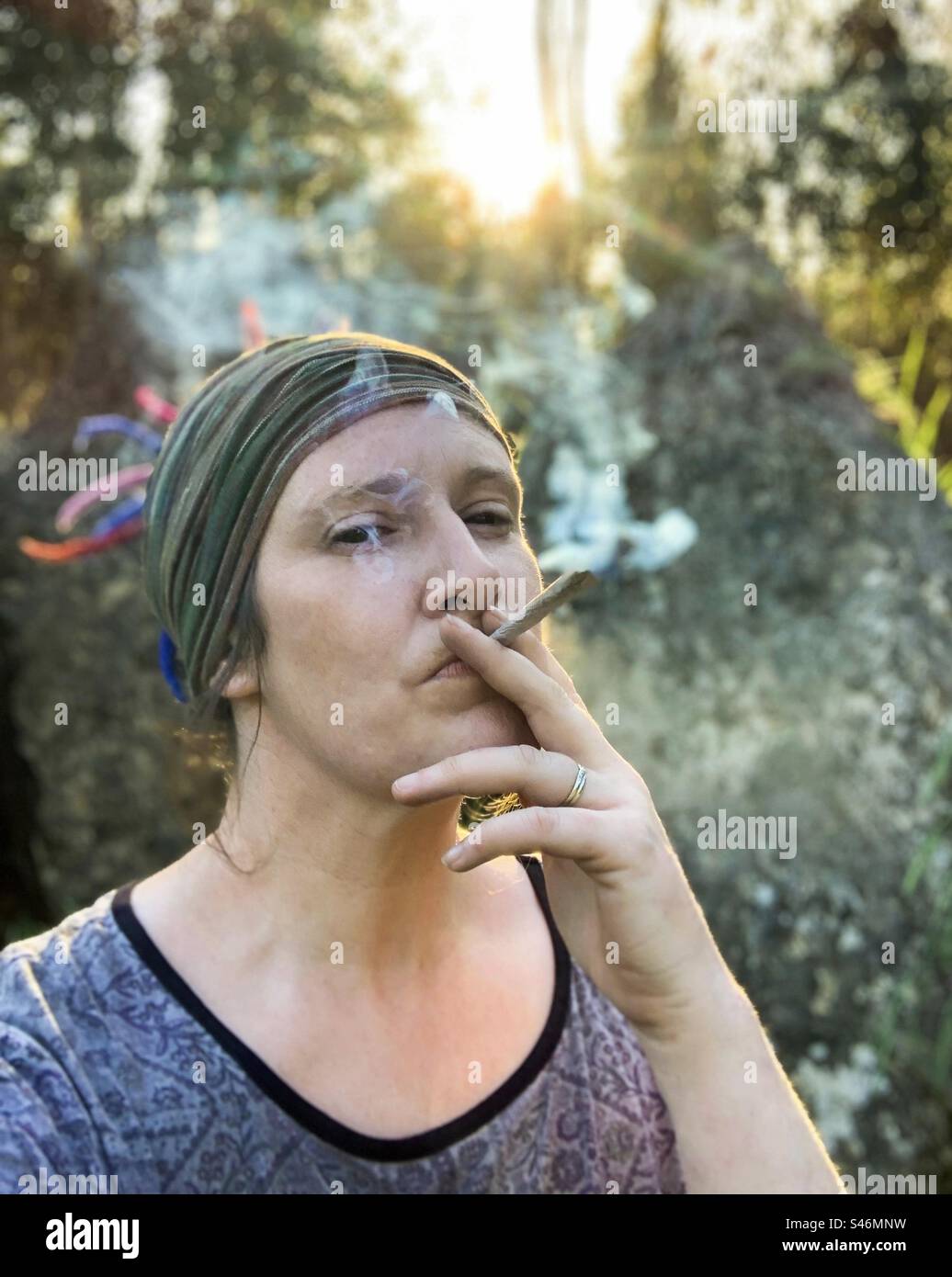 Femme fumant un gros joint au coucher du soleil Banque D'Images