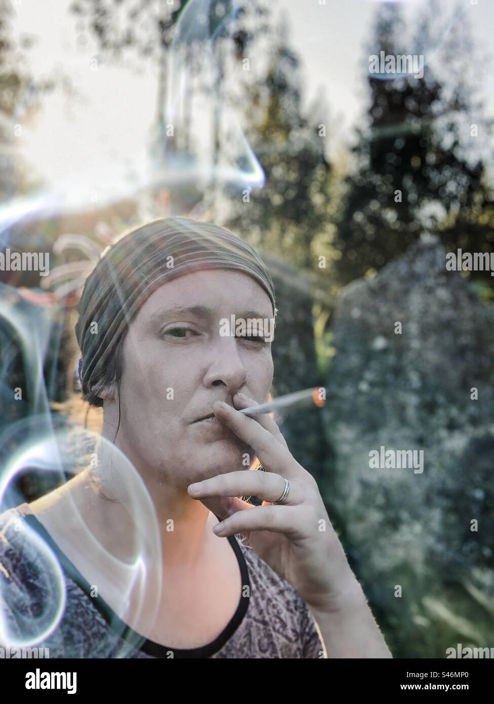 Femme fumant un gros joint au coucher du soleil Banque D'Images