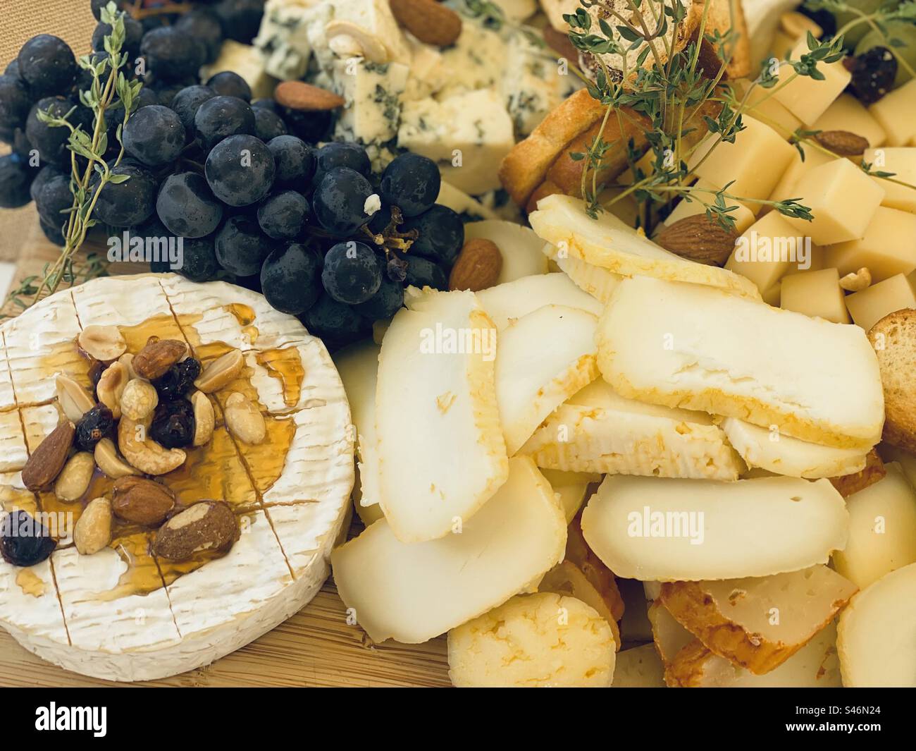 Plateau de fromages avec raisins, herbes, miel et noix. Cascais, Portugal, 2023. Banque D'Images