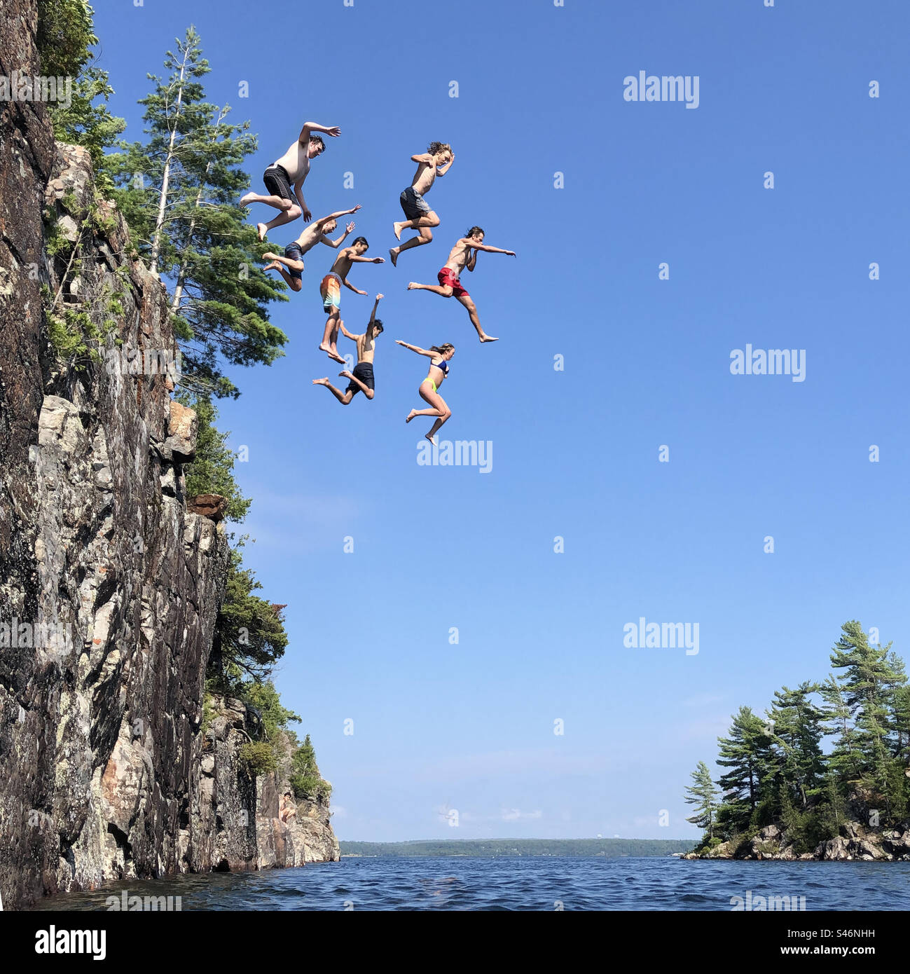 Groupe de personnes sautant tous en même temps d'une falaise dans l'eau. Trou dans le mur, Parry Sound Ontario. Banque D'Images