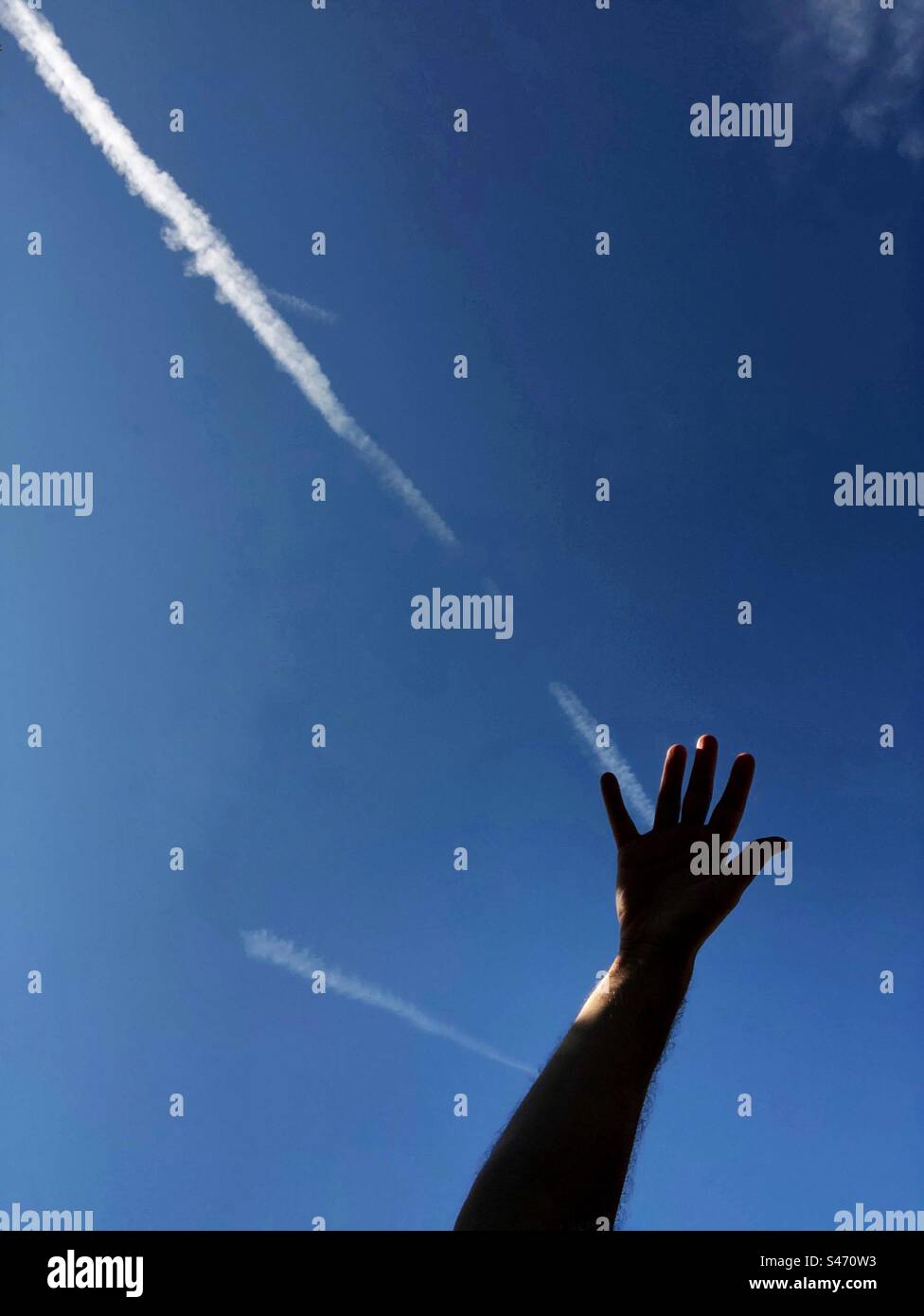 Main d'une personne alignée avec l'avion contrail contre le ciel bleu - Image de stock capturée avec un smartphone