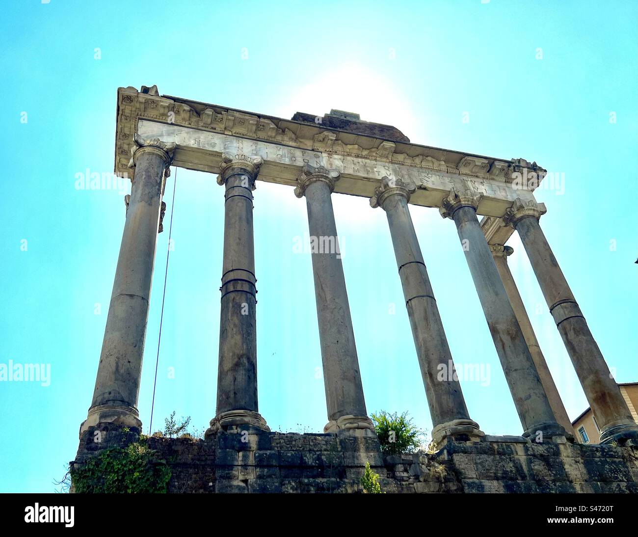 Soleil brille dans un ciel bleu clair au Temple de Saturne dans le Forum romain. Banque D'Images