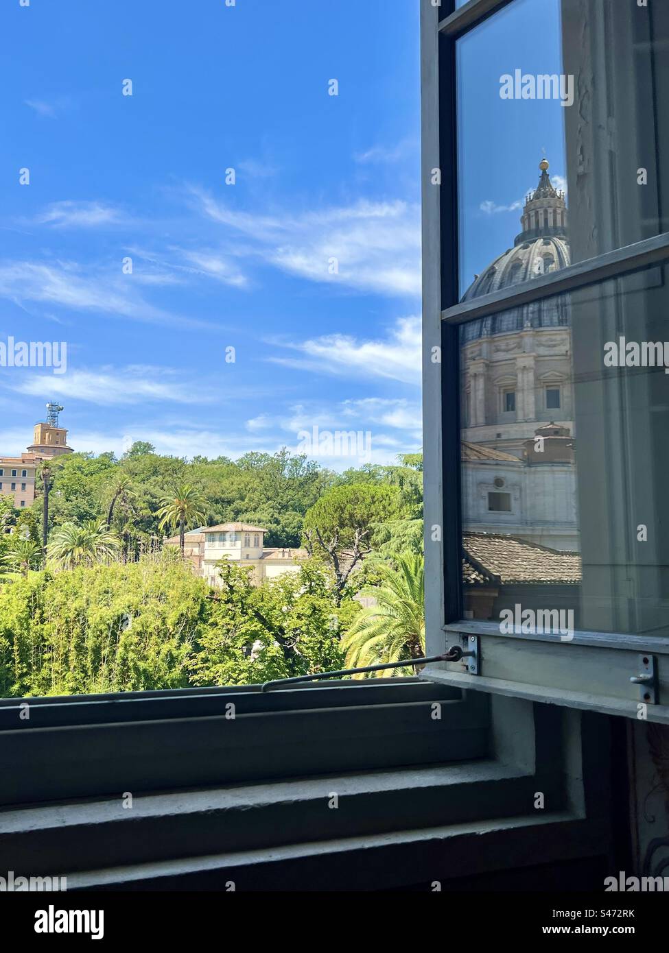 Regardant à travers une fenêtre ouverte au Musée du Vatican vers les jardins, avec le dôme de la basilique Saint-Pierre reflété dans le verre. - Image de stock capturée avec un smartphone