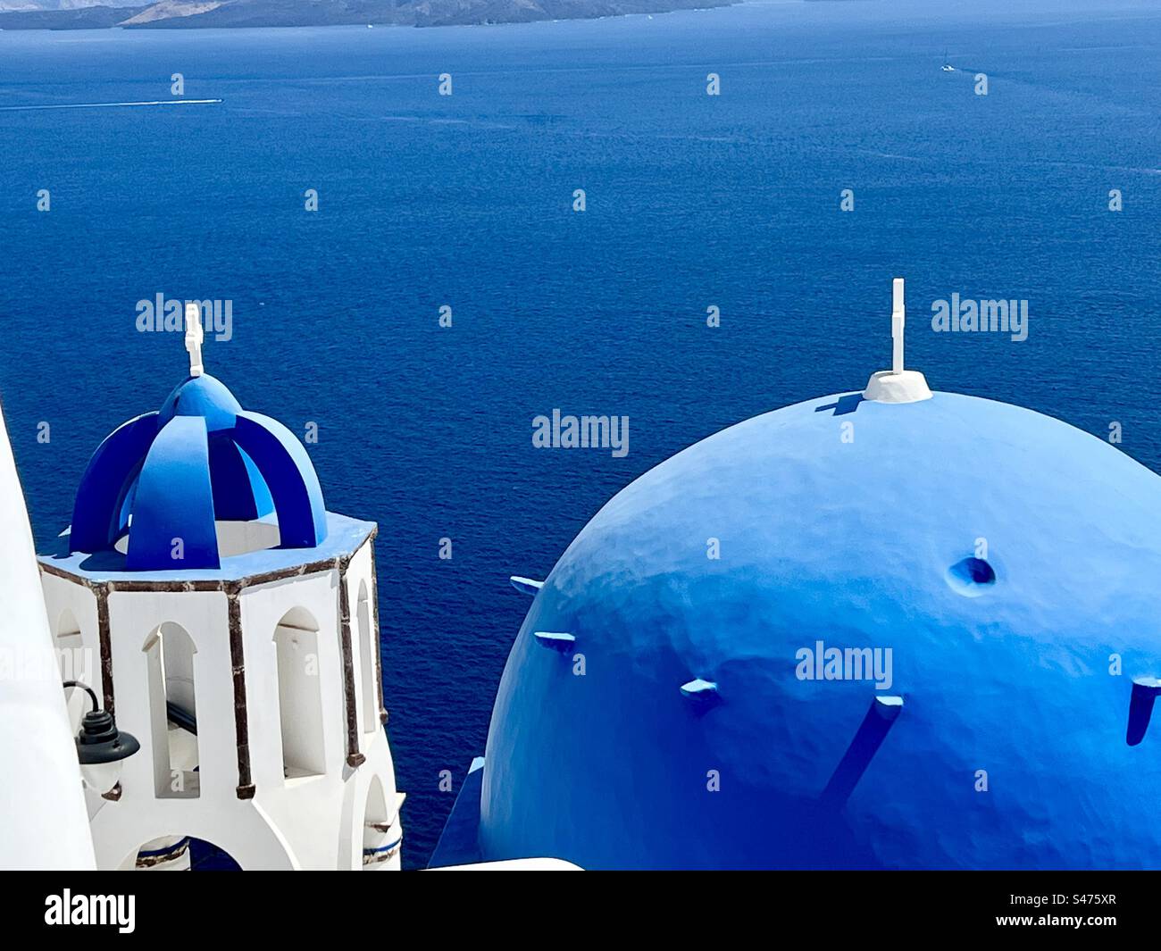 Tristement célèbre dôme bleu de l'église Saint Spyridon et son clocher en forme de dôme soutenu par la caldeira à Oia, Santorin, Grèce. Banque D'Images