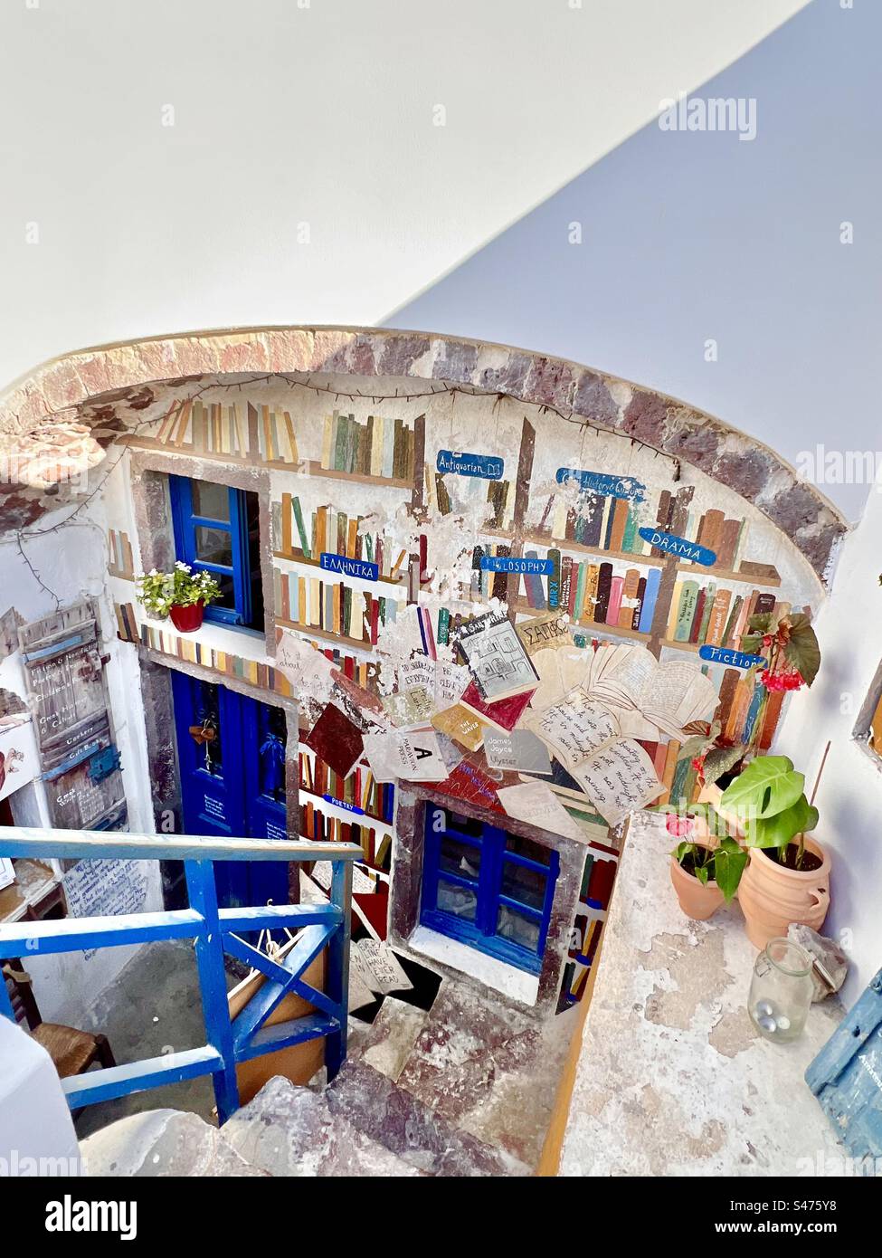 L'extérieur coloré d'une boutique à Santorin comprend des livres peints dans une peinture murale sur le mur sous une arche de brique. Oia, Santorin. - Image de stock capturée avec un smartphone