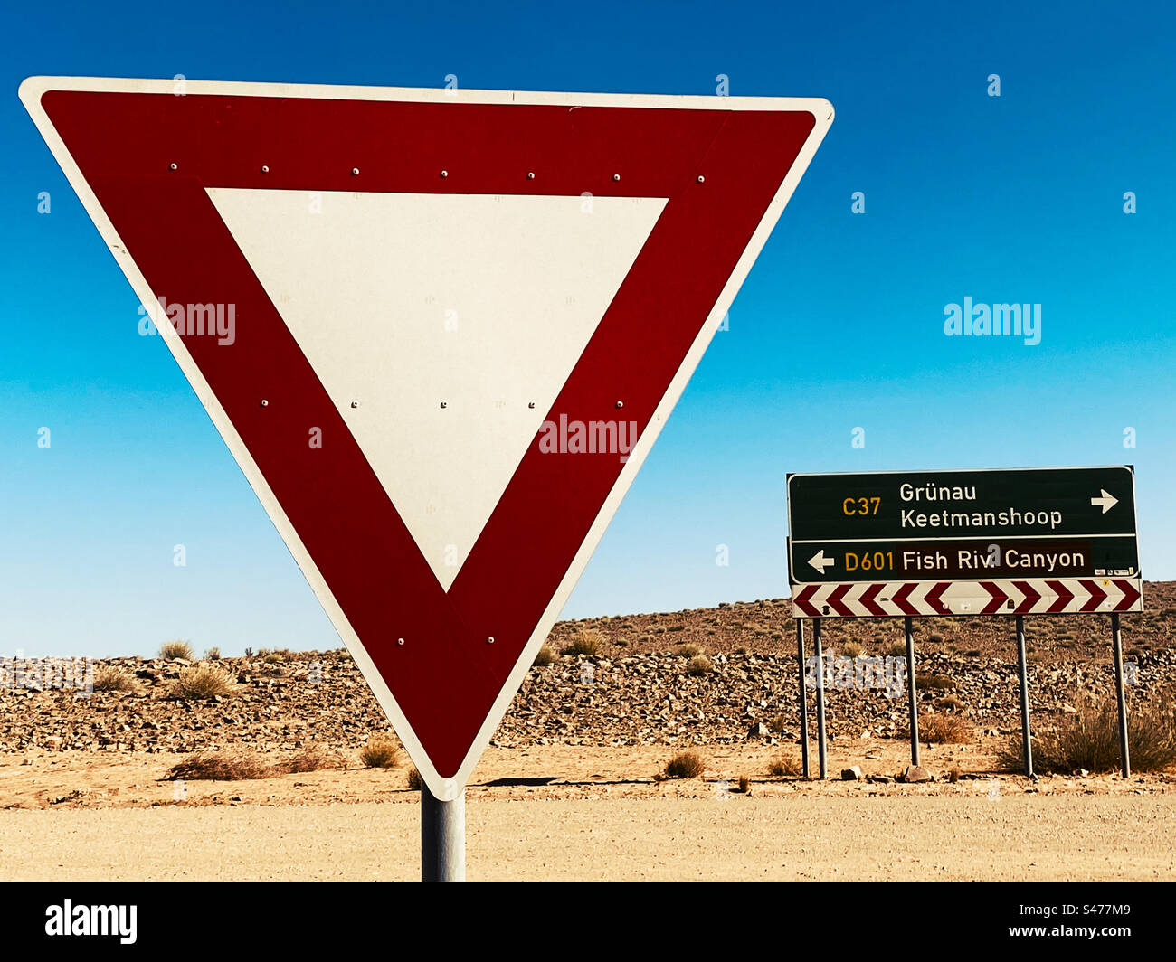 Un triangle d'avertissement rouge et un panneau routier sur un chemin de terre en Namibie Banque D'Images