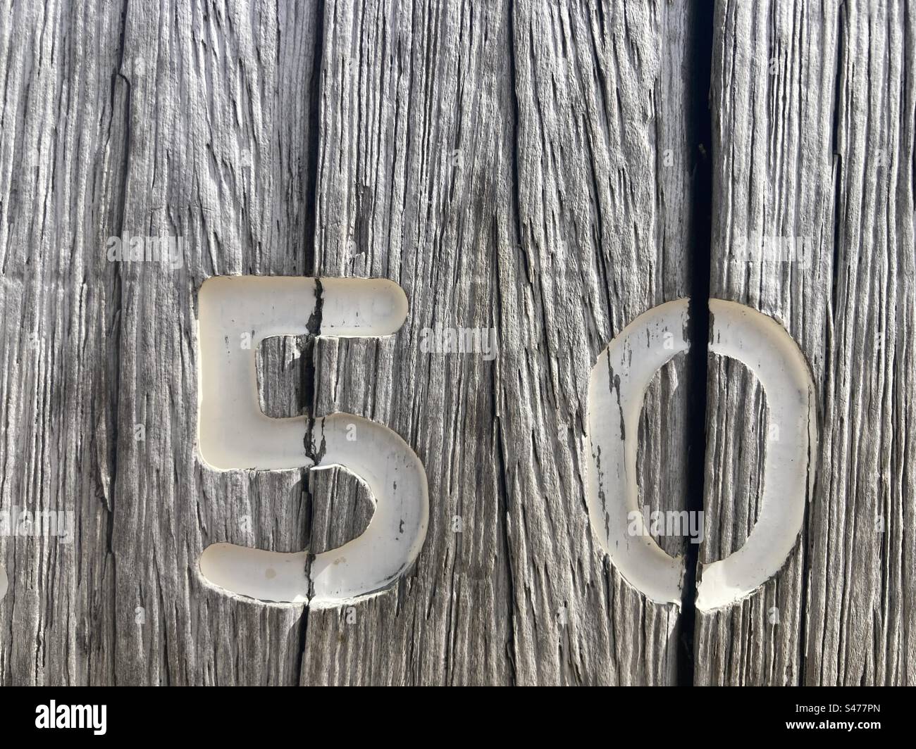 Un numéro 50 blanc peint sur un piquet en bois patiné - Image de stock capturée avec un smartphone